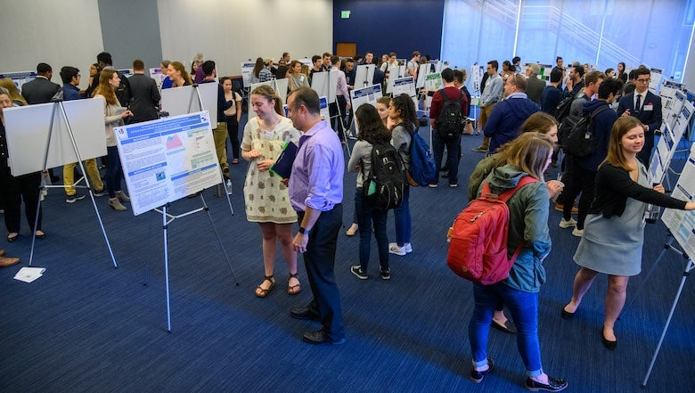 Students and faculty review posters at the Undergraduate Research Conference.