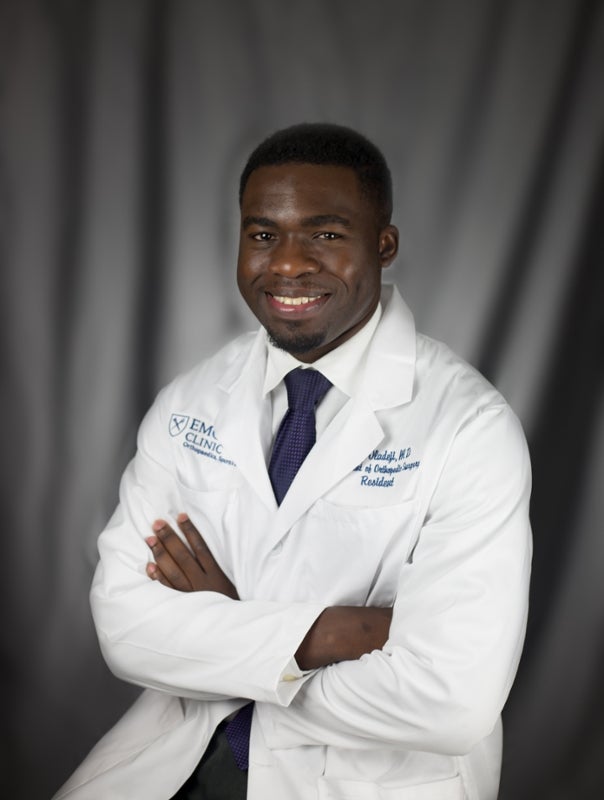 Dr. Philip Oladeji poses in a physician's clinical coat in a formal portrait.