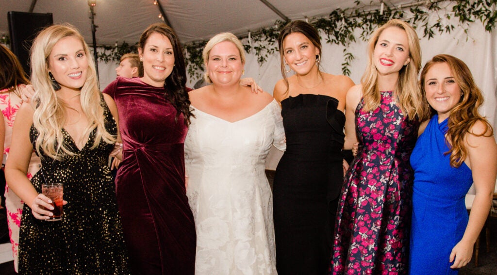 A photo at a wedding with five attendees posing with the bride.