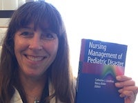 Catherine Joy Manz Goodhue poses holding a copy of her new textbook, Nursing Management of Pediatric Disaster.