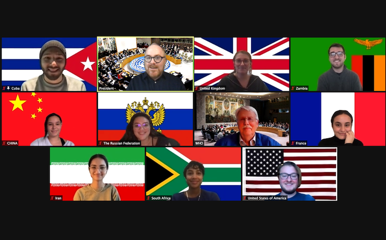 A Zoom screen of multiple student and faculty participants in a global health simulation with each student representing a different country and posing before the respective country flag.