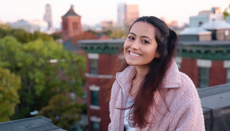 Shreya Arora (NHS'24) in an outdoor photograph with buildings in the skyline behind her.