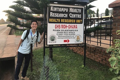 A student stands next to a sign in Ghana