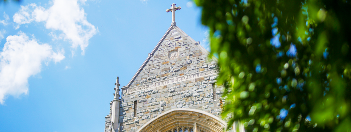 Detail of a cross atop a chapel against the blue sky