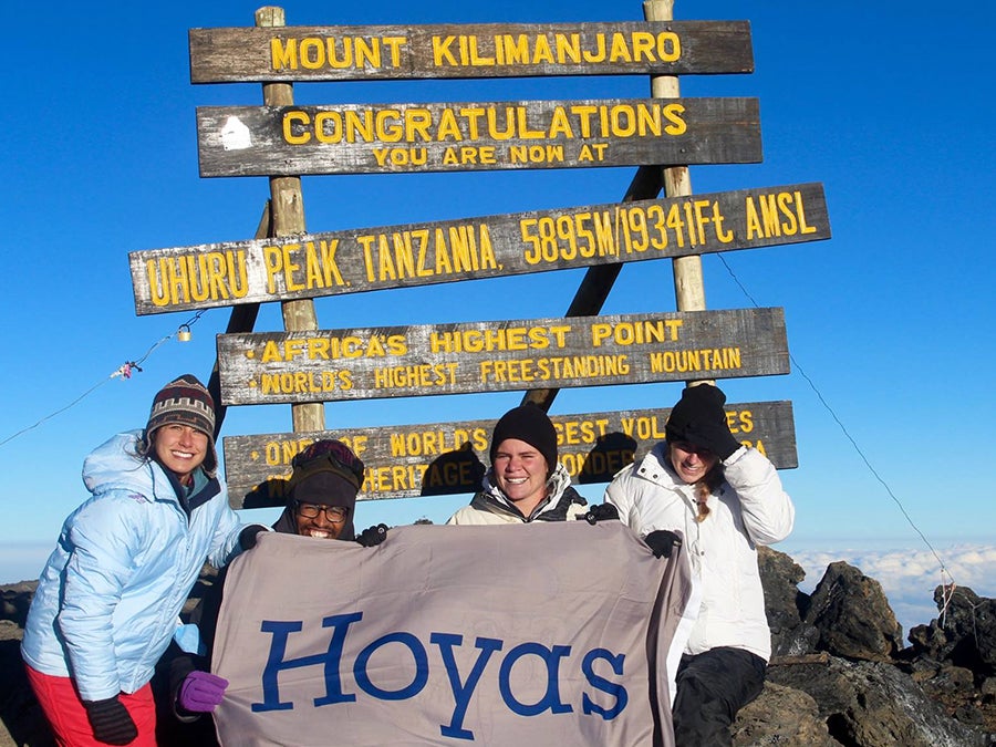 Several students sit with a Hoya banner atop Mount Kilimanjaro