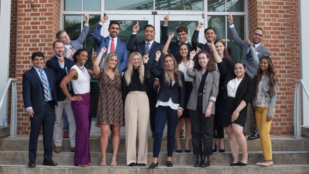 A group of students hold a finger in the air
