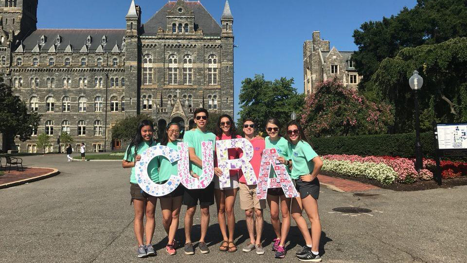 A group of students hold letters that spell the word CURA