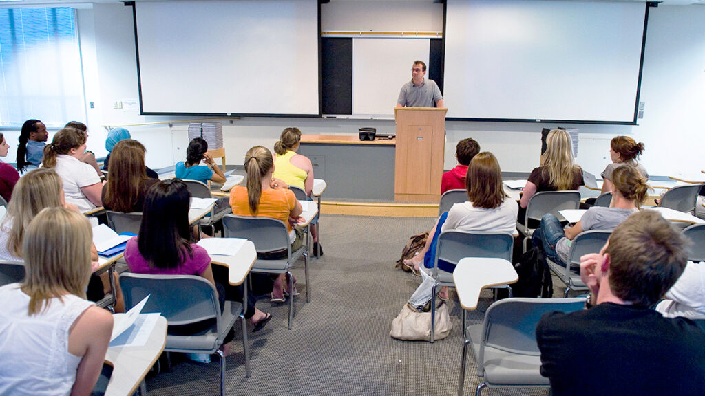 A professor speaks to a class from a podium