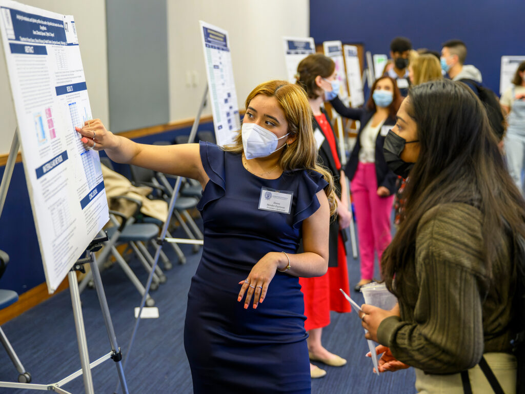 A student presents her research to another student at a conference