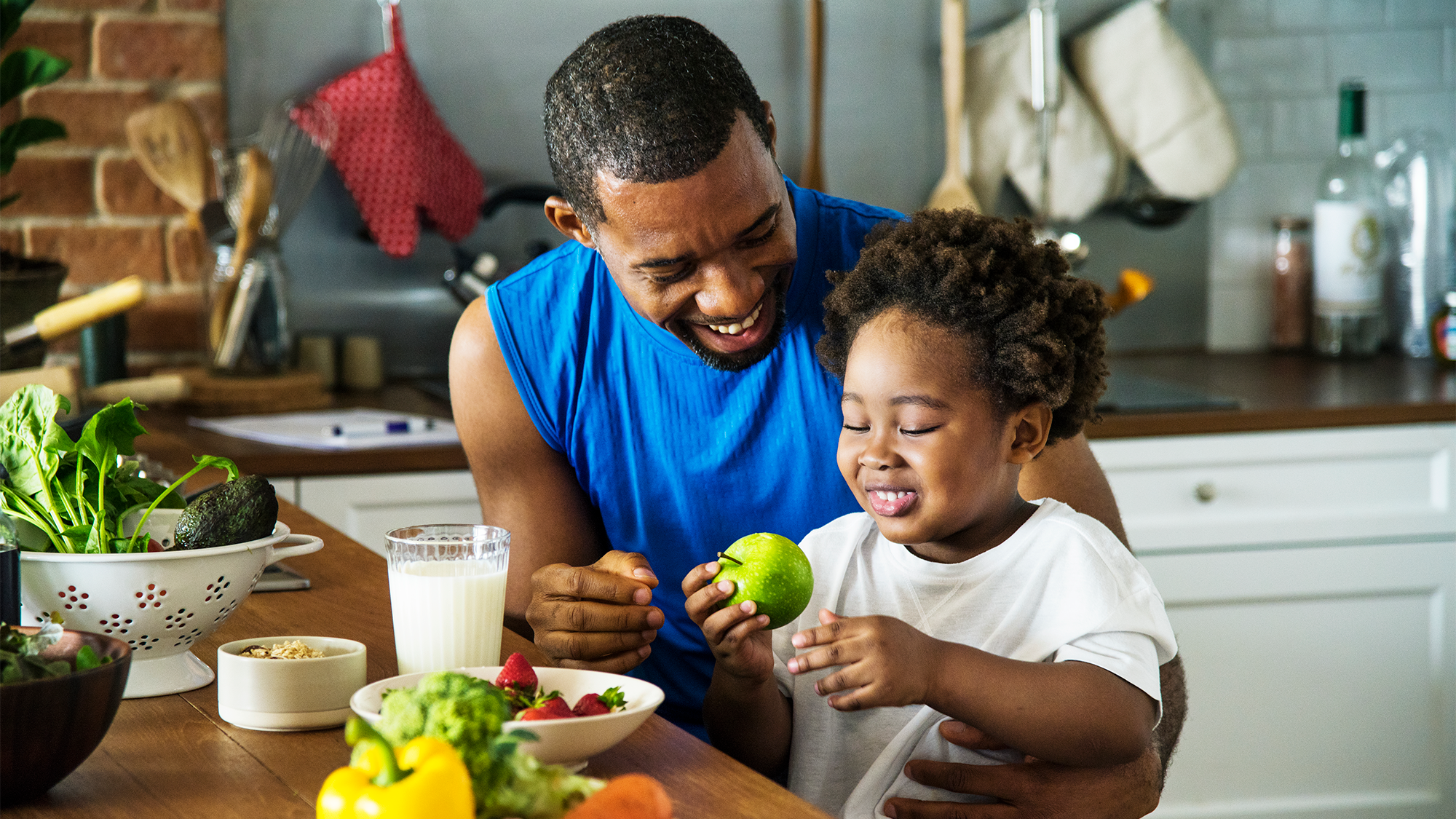 A father and young child interact in a kitchen