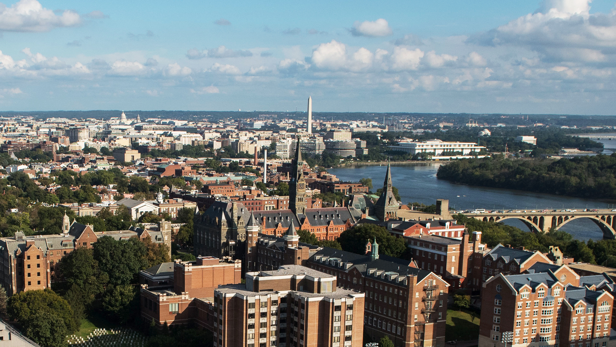 An aerial view of Georgetown's campus with downtown DC in the far background