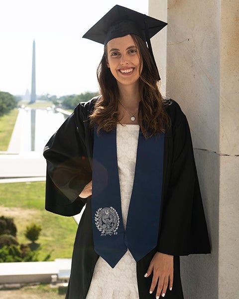 Clara Ortega in graduation garb with the Washington Monument in the background