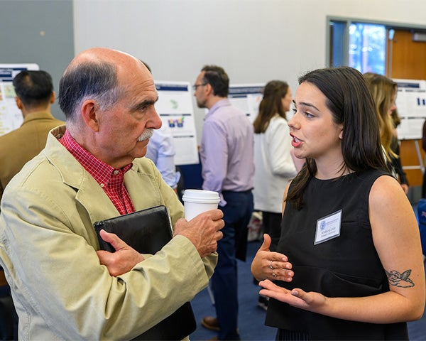 Two people talk in a crowded room