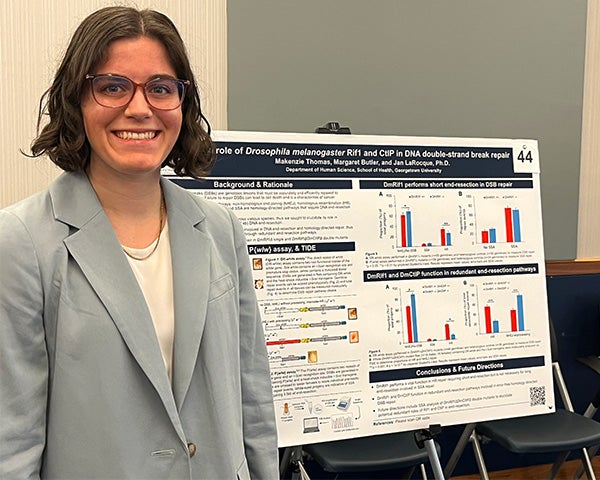 a woman stands in front of an academic poster