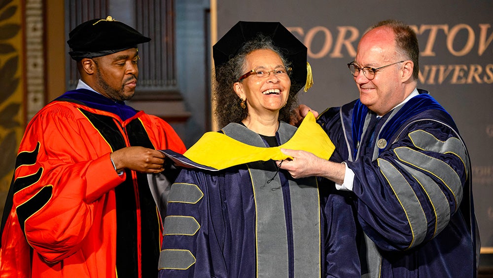 Dean King and President DeGioia lower a doctoral hood over Dr. Jones' head