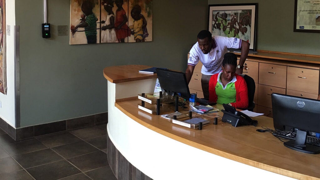 Two people work at a reception desk in a hospital