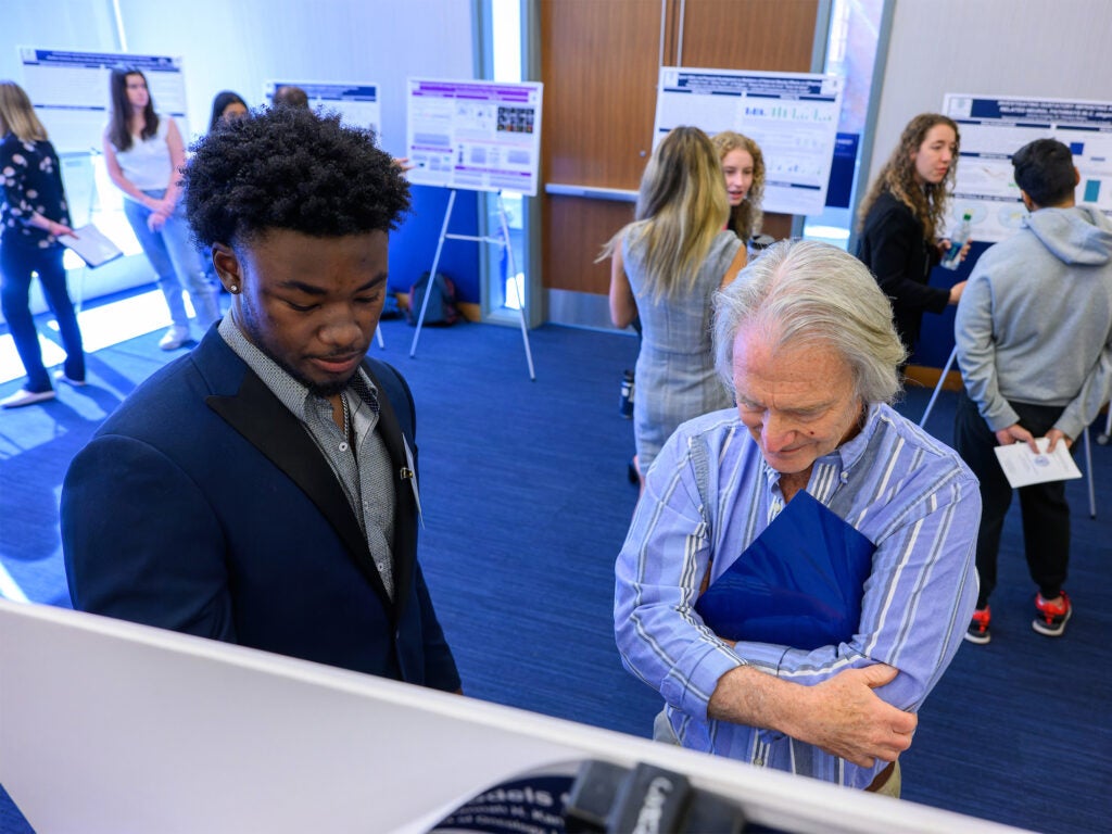 A student explains his research poster to a faculty member at the Undergraduate Research Conference