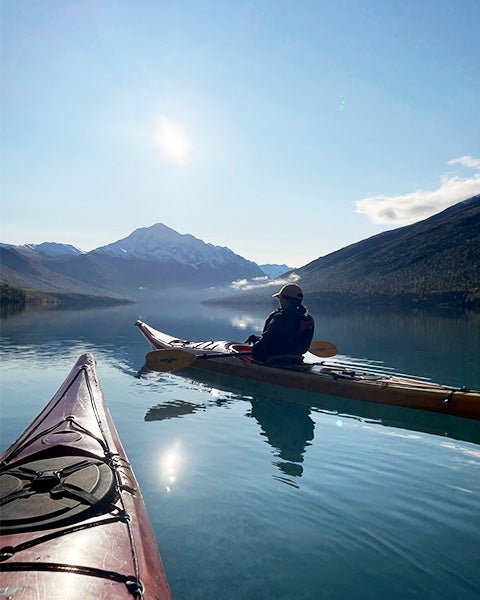 Two kayaks ply the still waters of an Alaska landscape