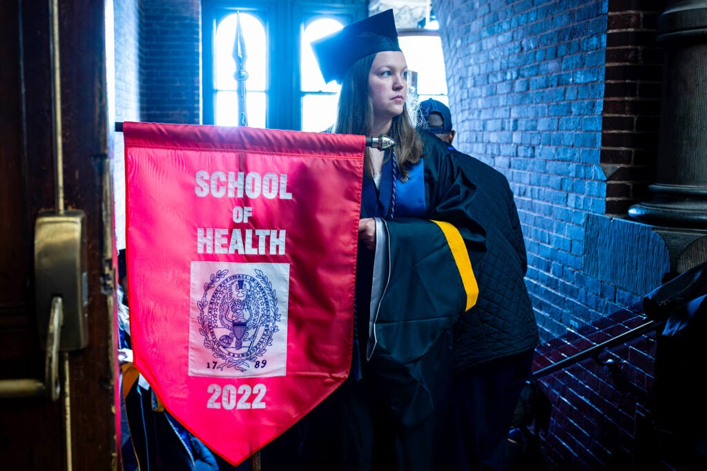 A student carries the School of Health banner up the stairs at Gaston Hall