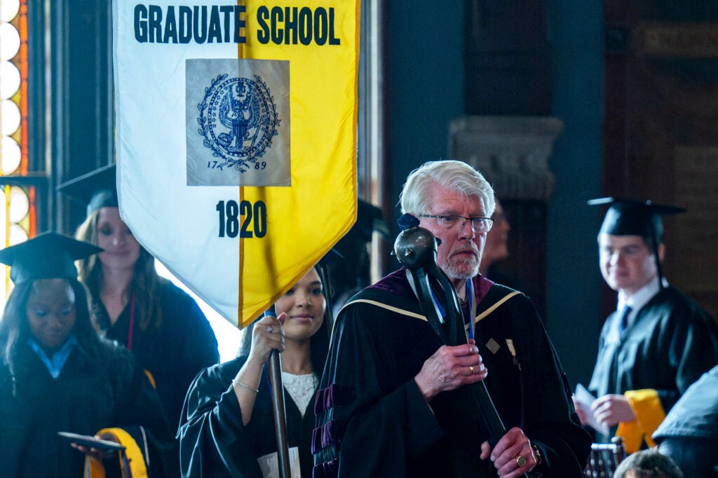 Students process into Gaston Hall in a line behind the master of ceremonies holding the ceremonial mace