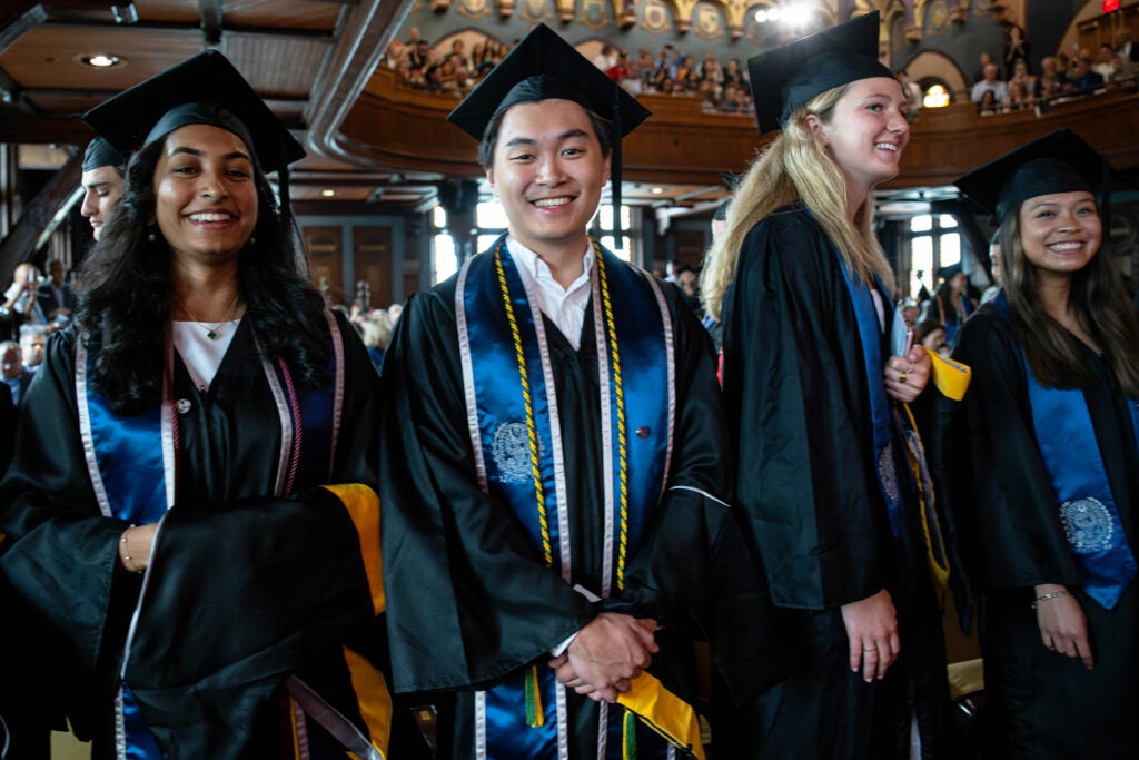 Master's students hold their ceremonial hoods and wait in line for their chance to walk the stage