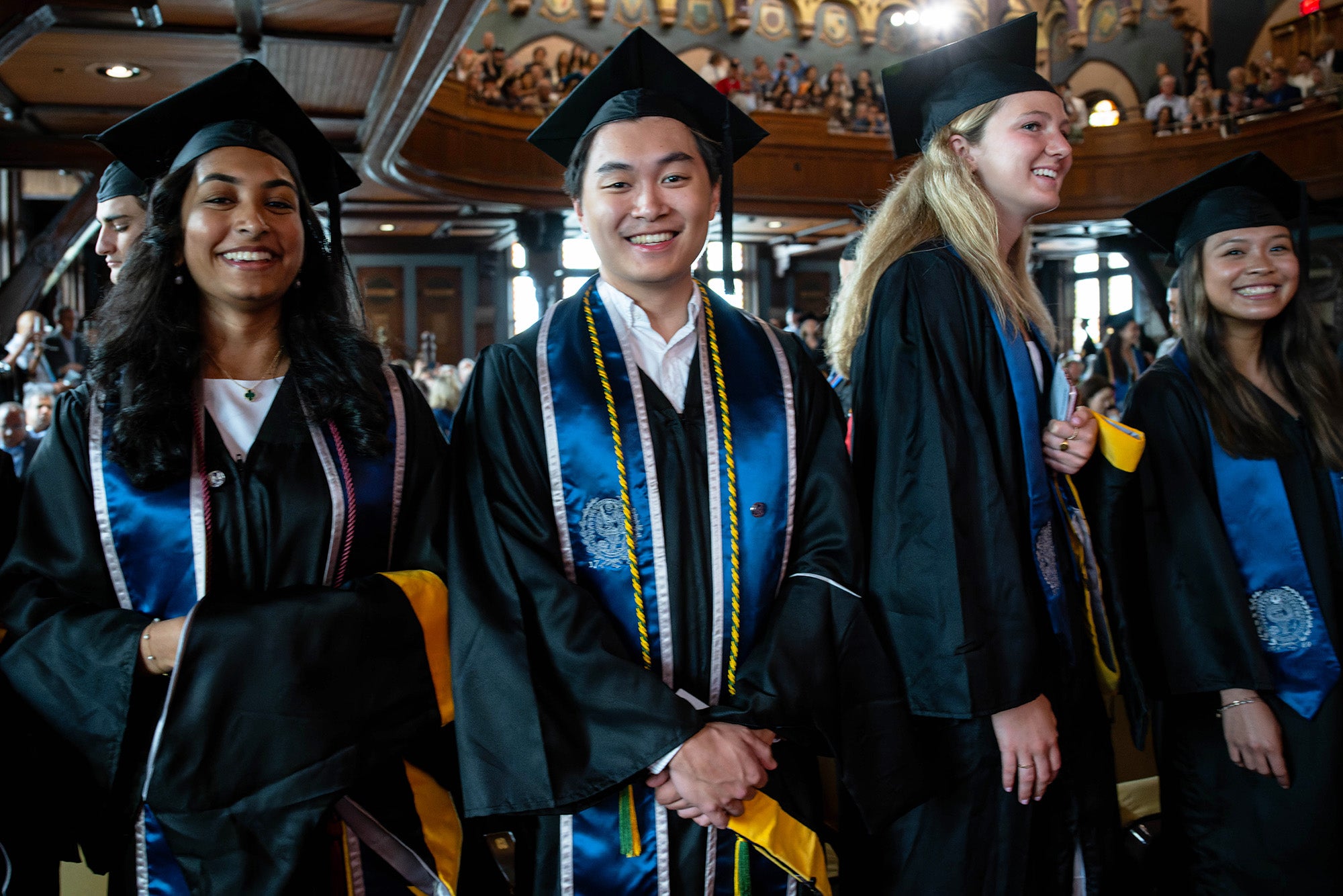 Master's students hold their ceremonial hoods and wait in line for their chance to walk the stage