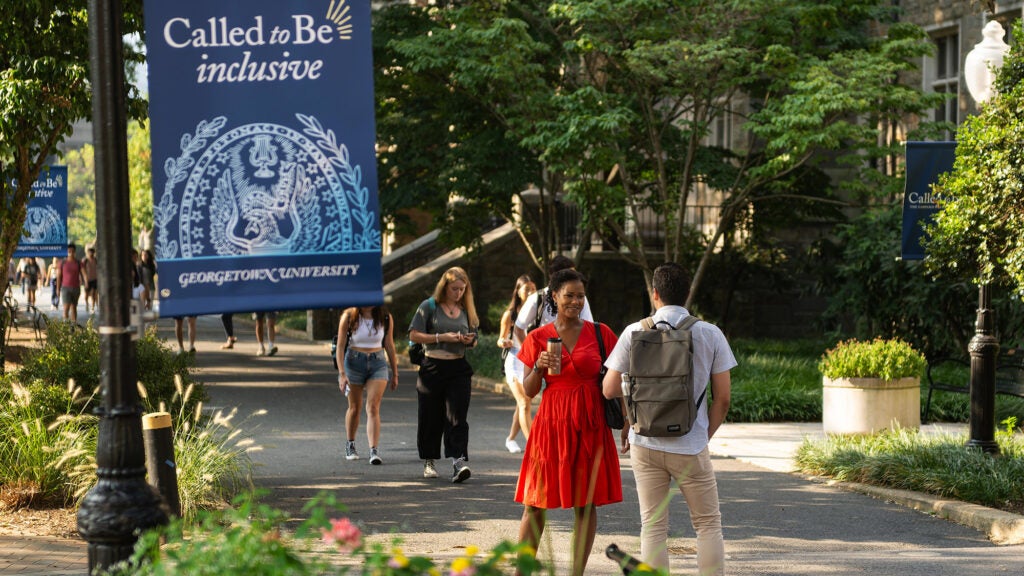 Students walk on a pathway through campus with a Called to Be Inclusive banner prominently displayed nearby