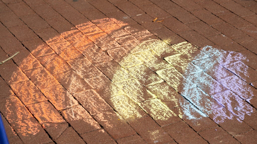 A rainbow drawn in chalk on a brick sidewalk