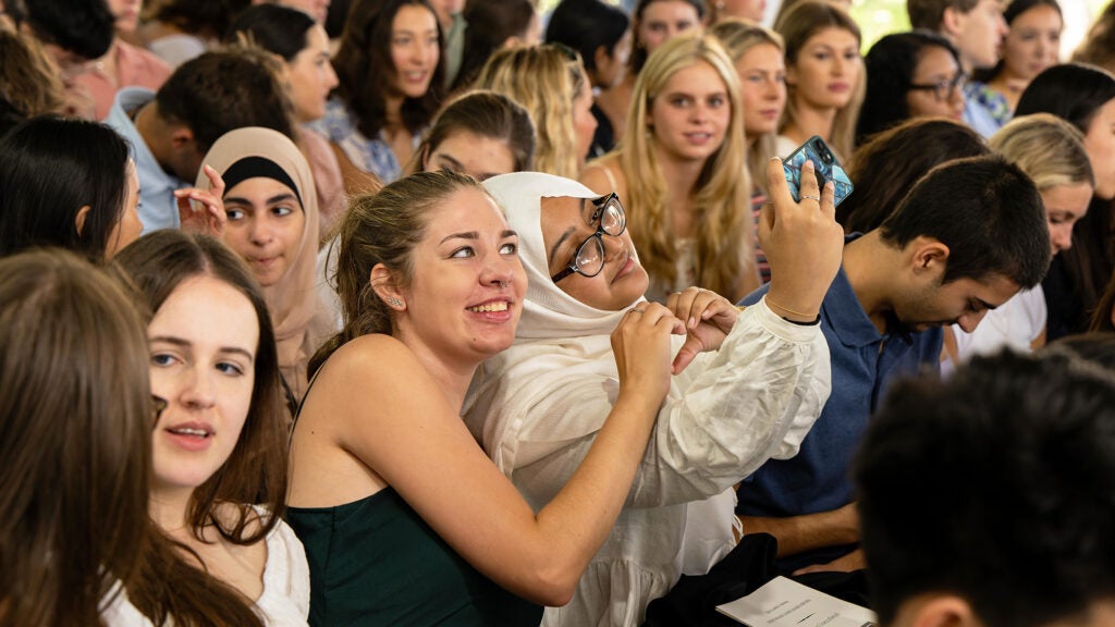 Two students take a selfie amid a crowd during new student orientation