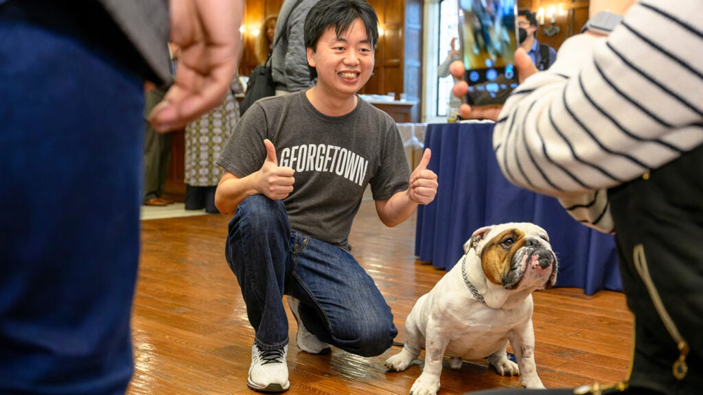 A man gives a two thumbs-up sign as Jack the bulldog sits patiently