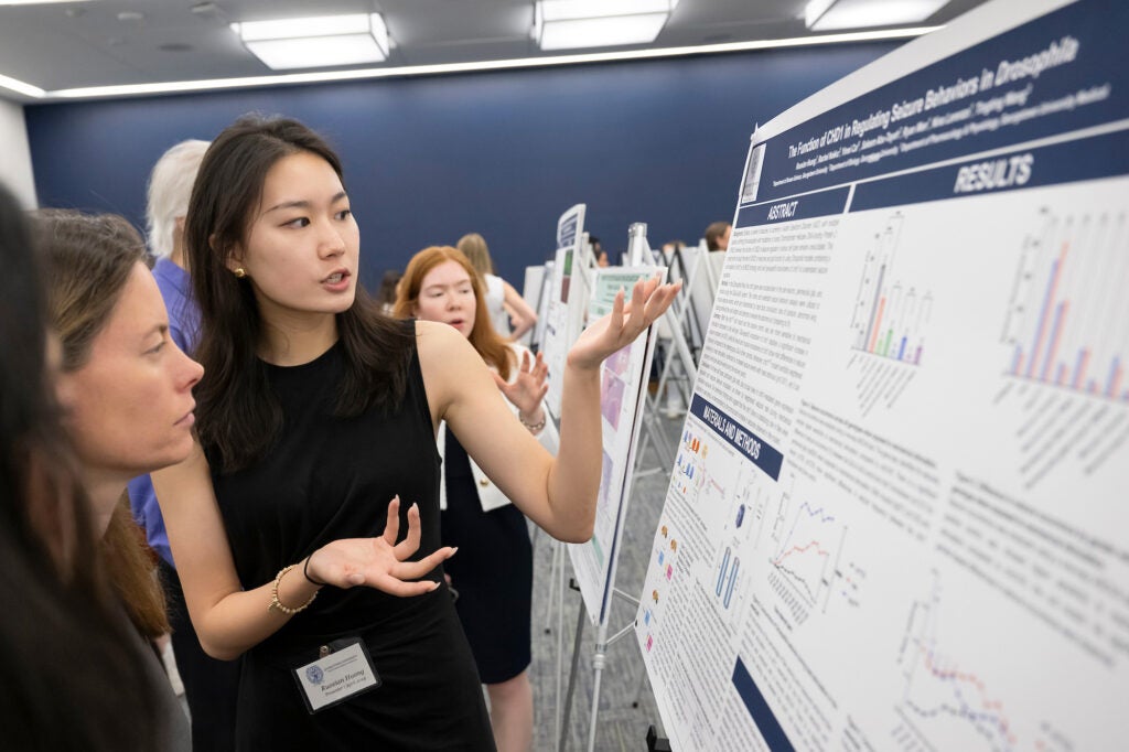 A student explains her research poster to Professor Blythe Shepherd