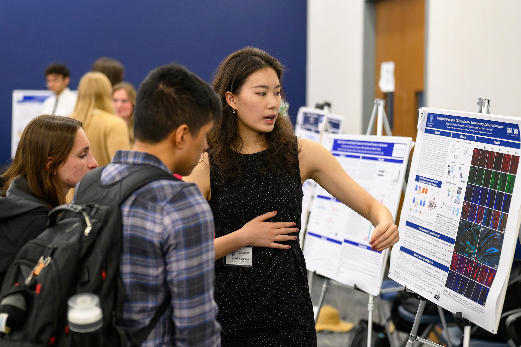 A female student explains her poster to two other students