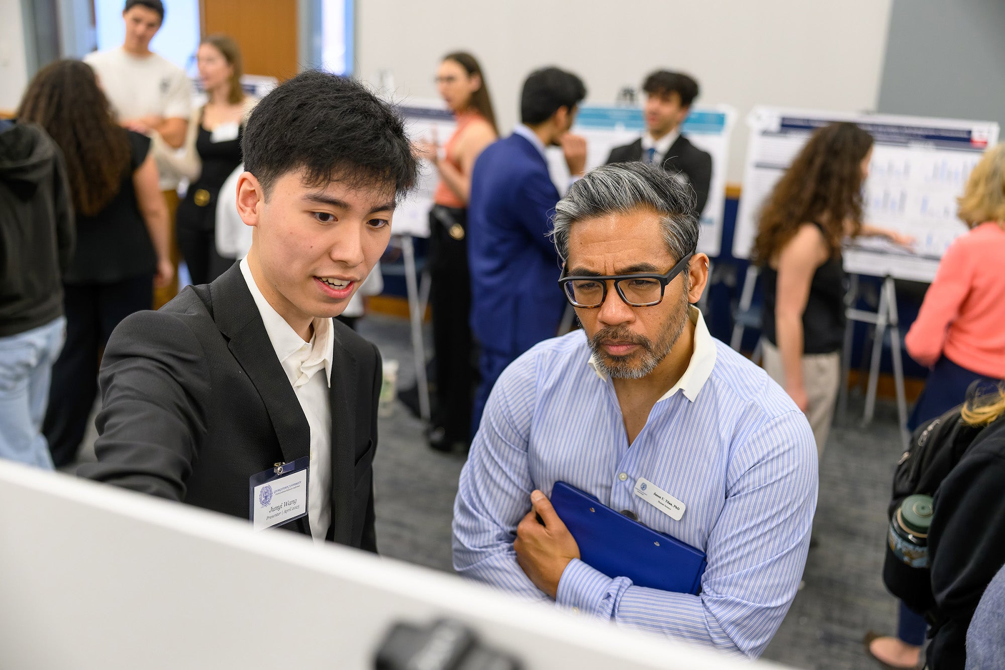 A student explains his poster to Dr. Tilan