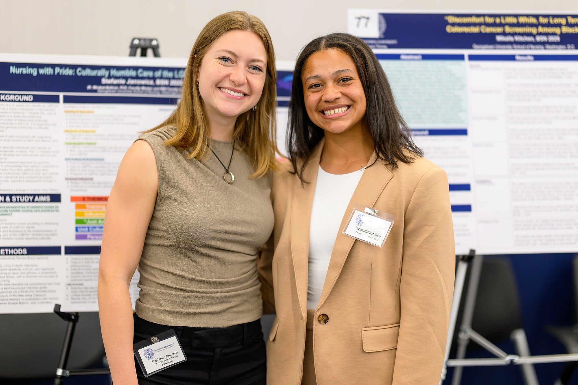 Two female students stand together before their posters