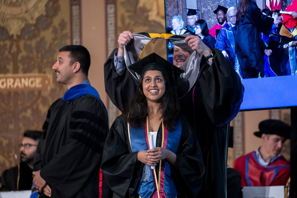 A student receives a sash from John Kraemer during commencement