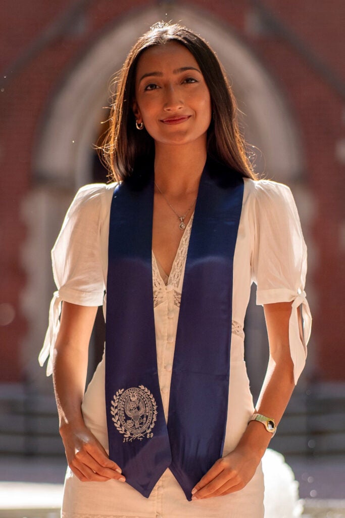 Shagun Gandhi stands in front of Dahlgren Chapel wearing a blue stole with the Georgetown seal on it