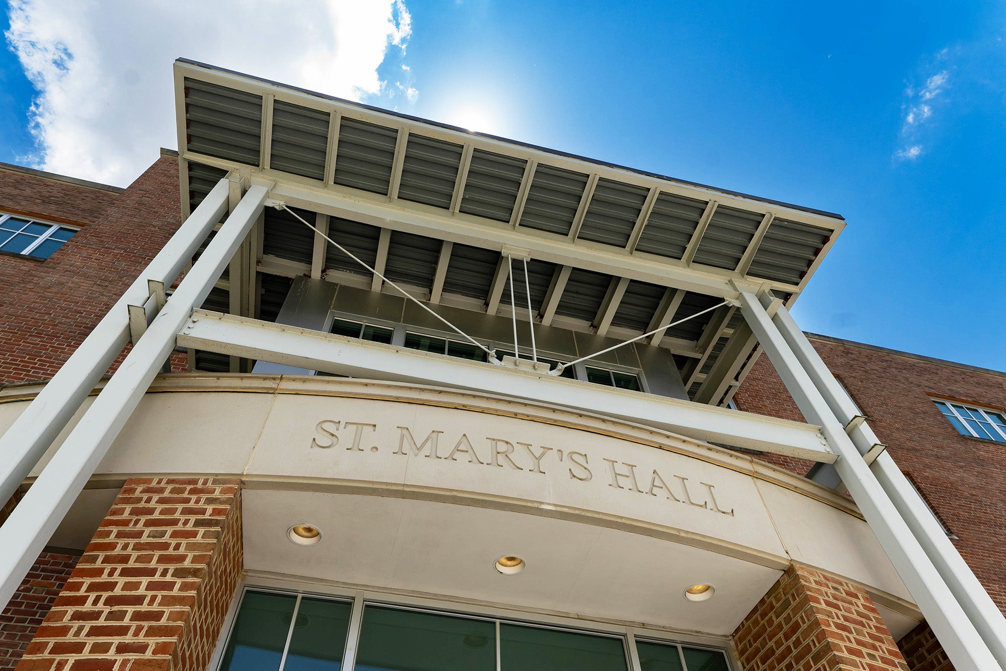 The front of St. Mary's Hall with the sun peeking over the roof
