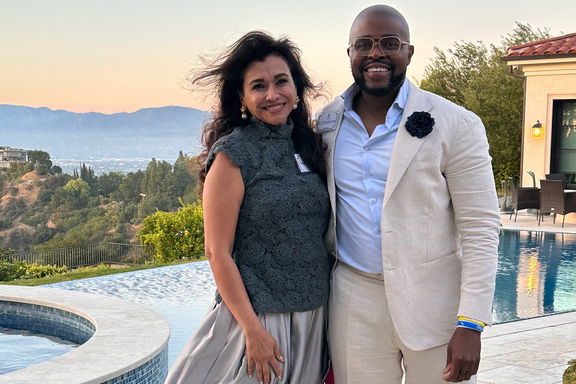 Deborah Sawaf and Christopher King stand together before a pool and view of Los Angeles