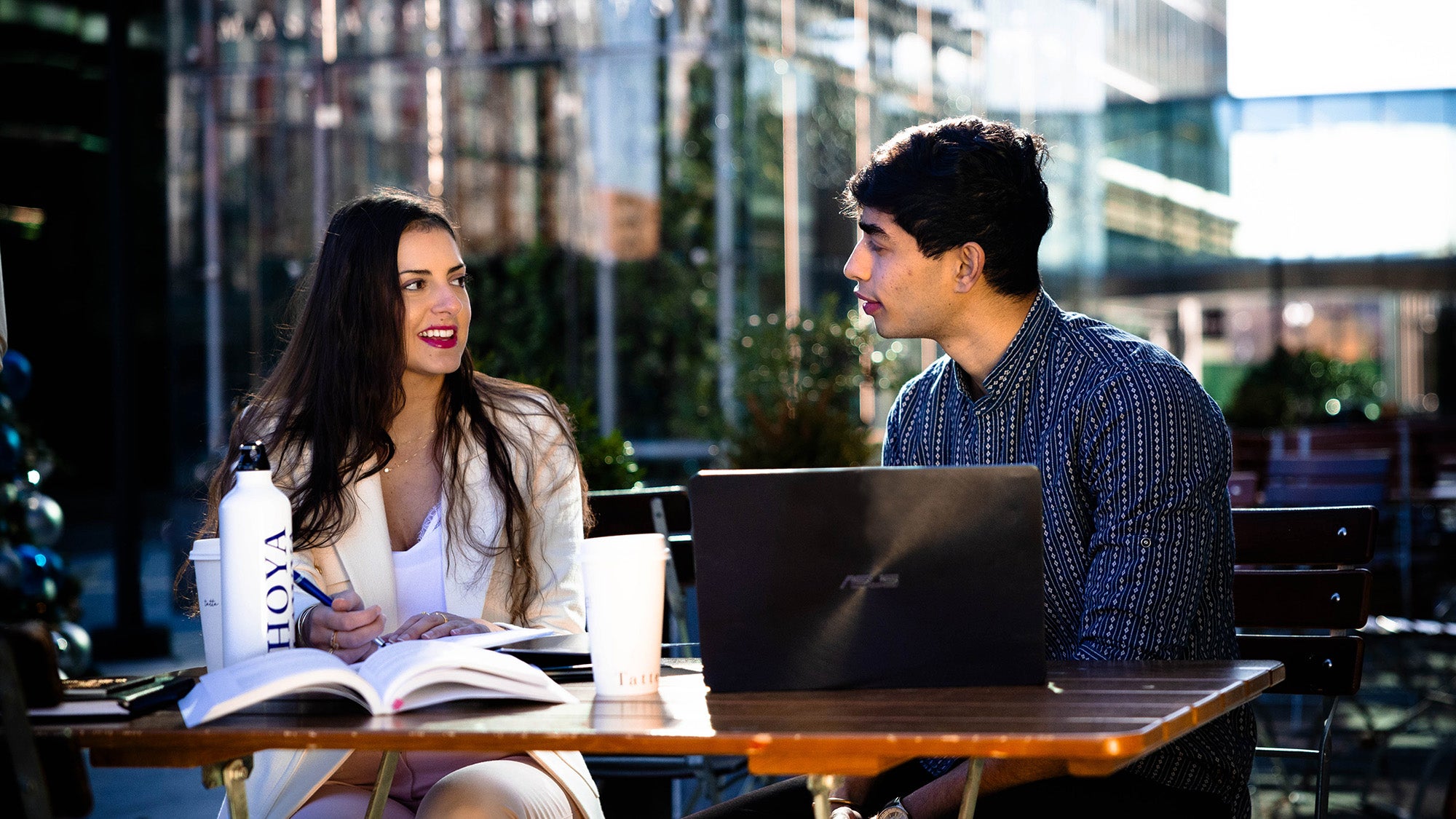 Two students converse while studying at a table