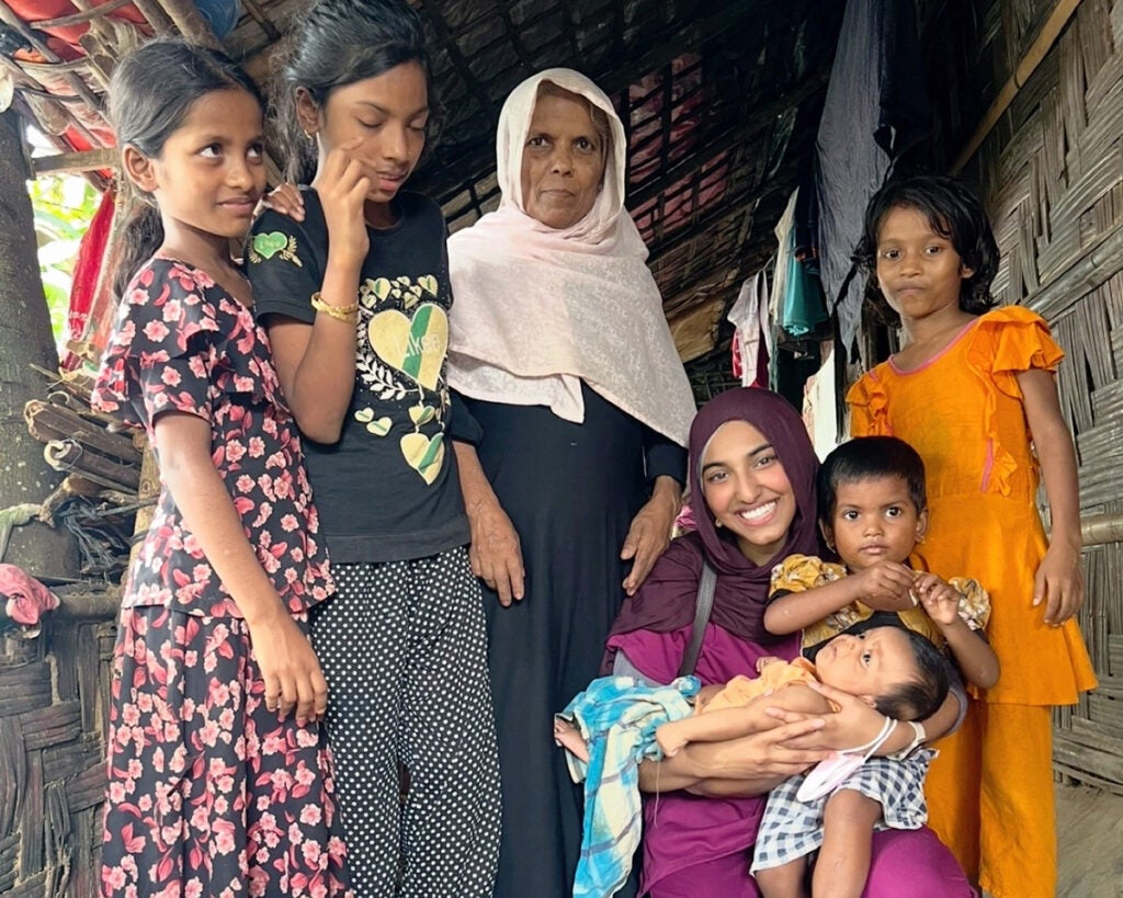 Isra Satiar holds two small children while four individuals stand next to her