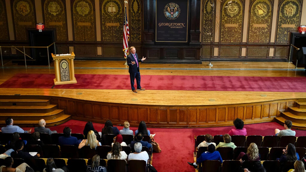 Quint Studer speaks from the stage in Gaston Hall