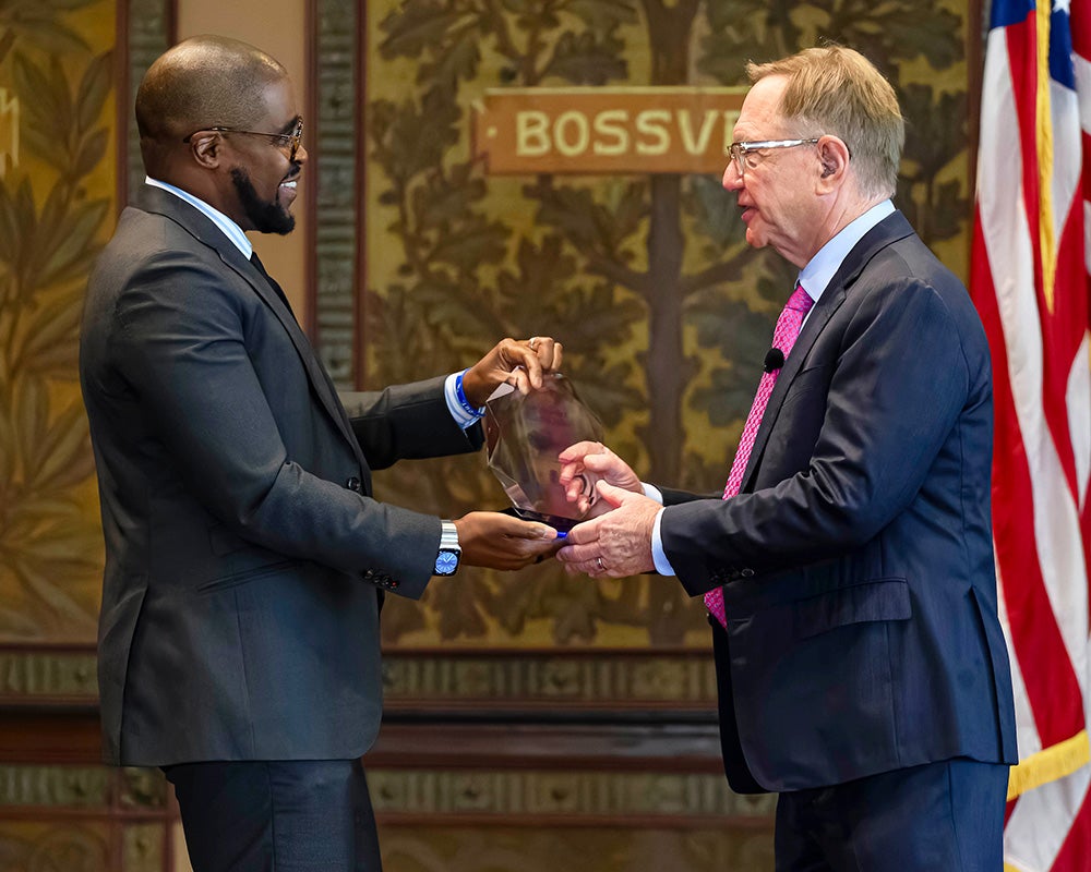 Christopher King presents Quint Studer with an award made of glass