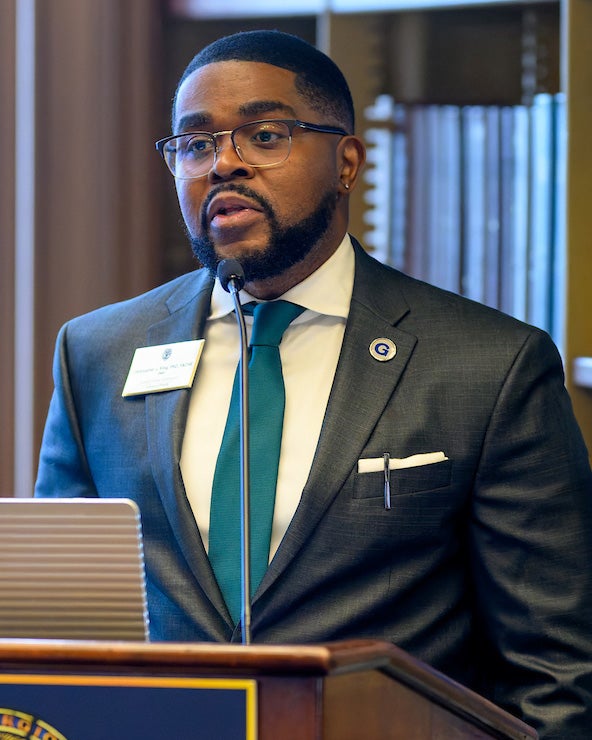 Christopher King speaks at a podium in Riggs Library