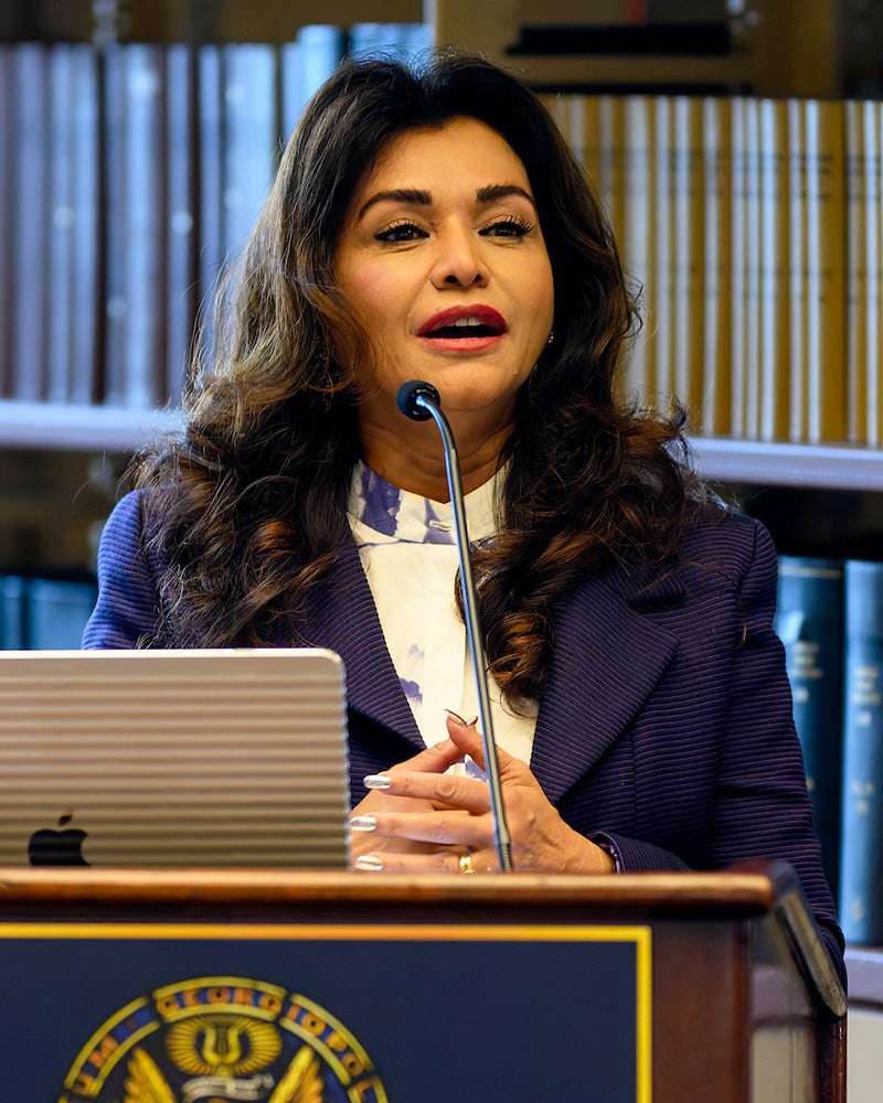 Deborah Sawaf speaks at a podium in Riggs Library