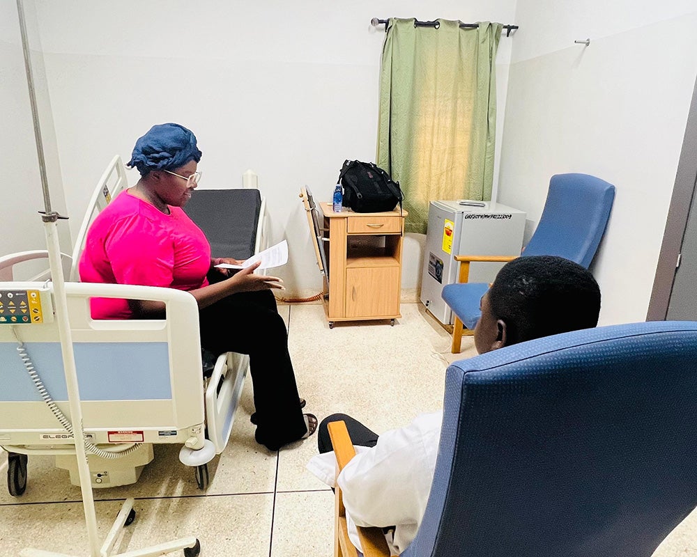 Wenegieme interviews a patient in a hospital room