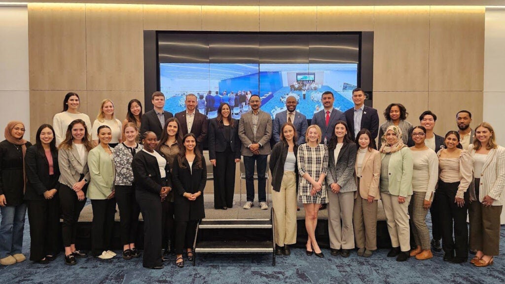 A large group of MHSA students and faculty stand together in a conference room