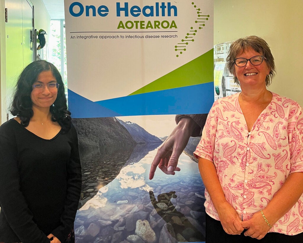 A student and her mentor stand in front of a large poster