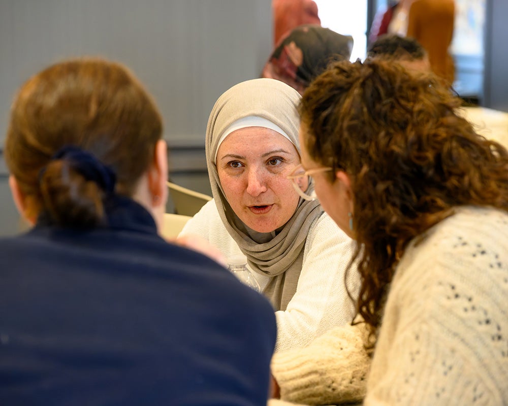 Global health preceptor Diana Arabiat speaks with two individuals while seated at a table