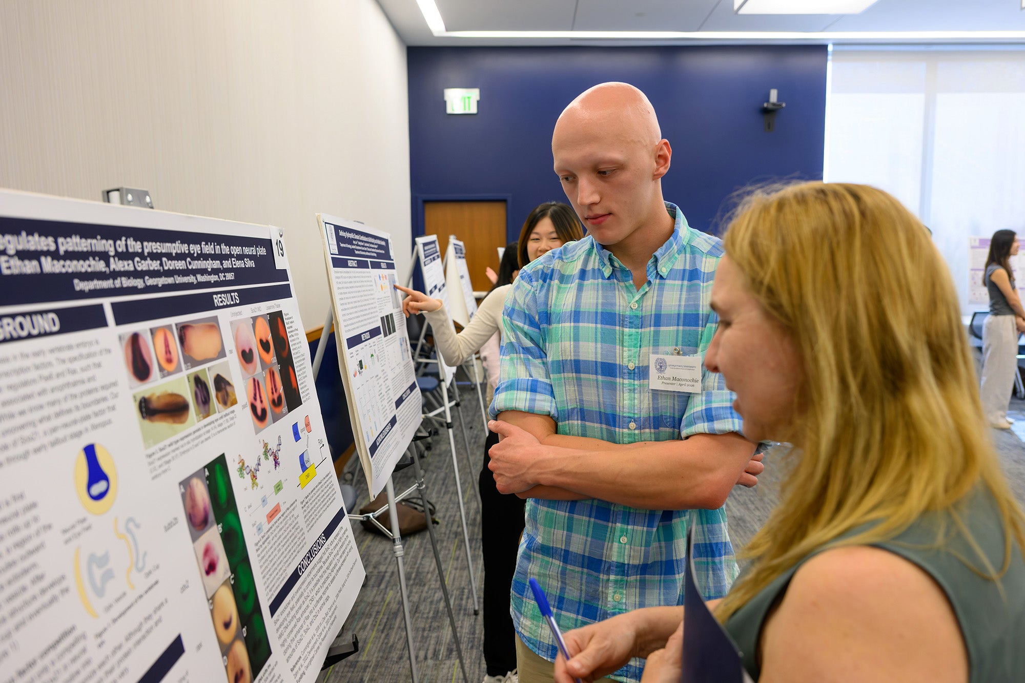 Ethan Maconochie explains his research to a conference attendee