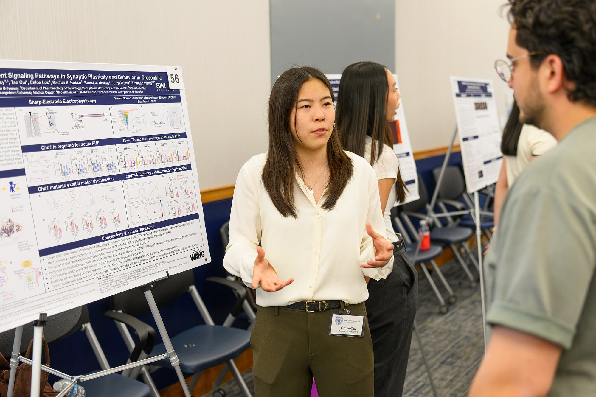 A student explains her poster to a conference attendee